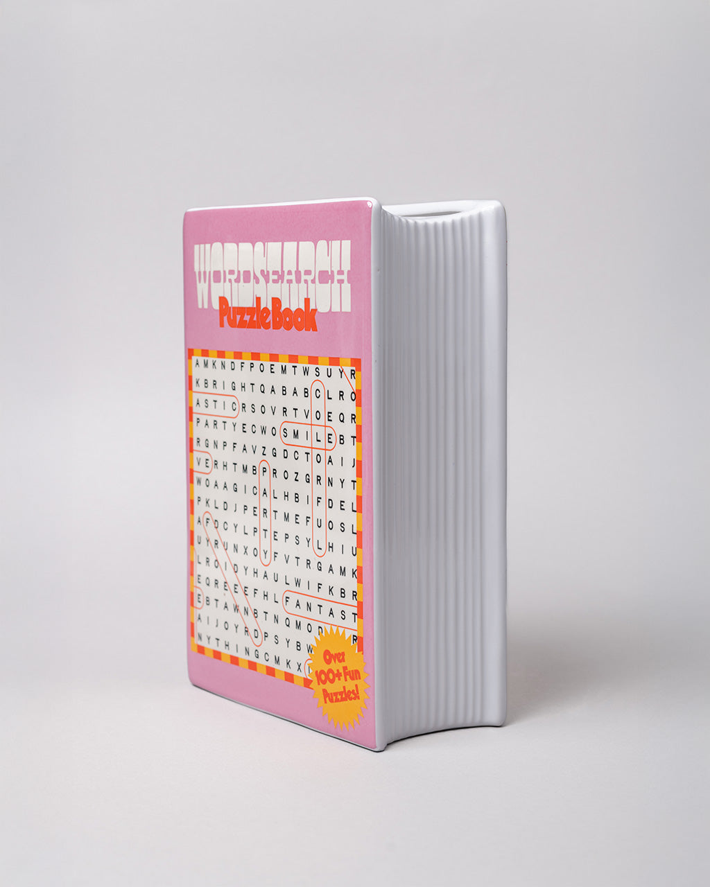 side view of textured 'pages' of pink word search puzzle book shaped ceramic vase