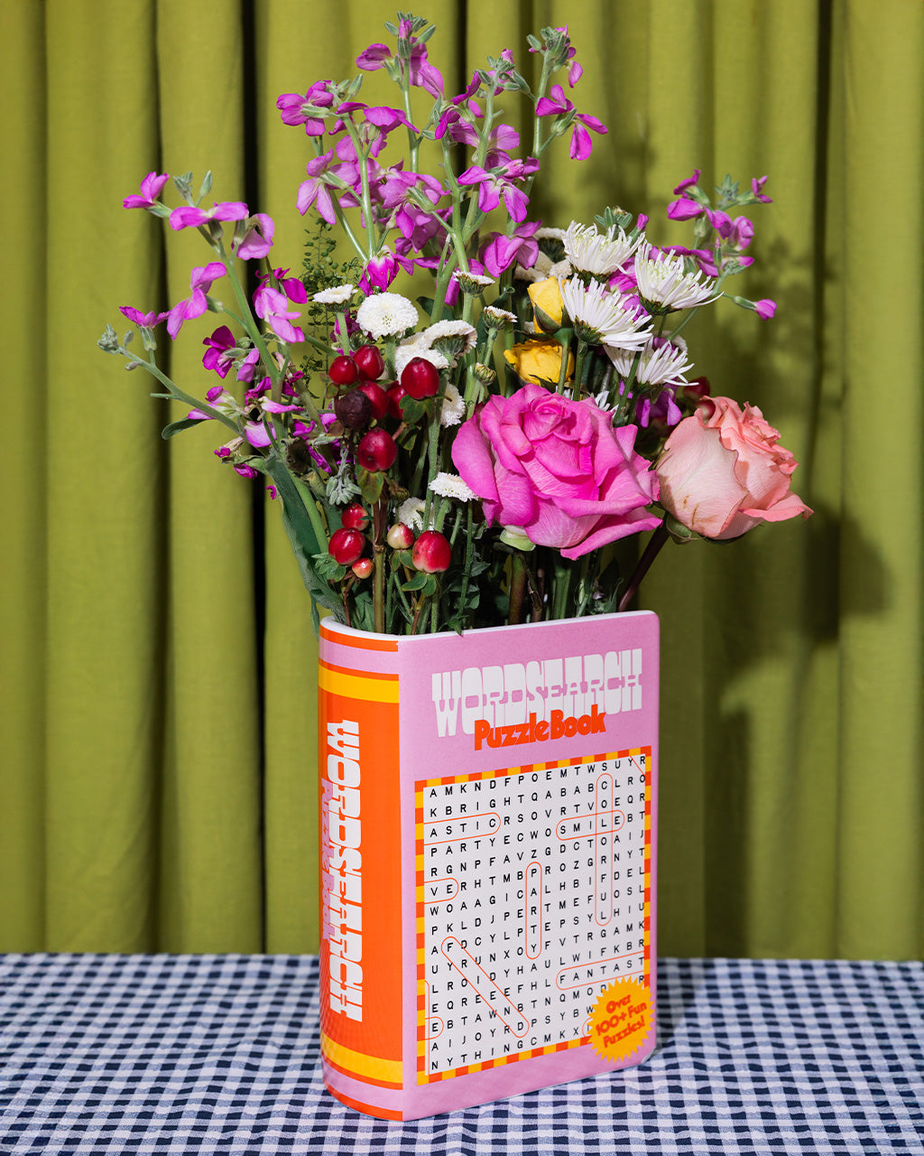 pink word search puzzle book shaped ceramic vase with a bouquet of colorful flowers inside