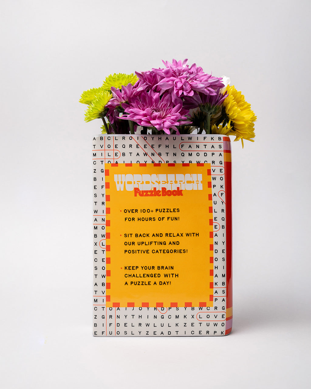back view of pink word search puzzle book shaped ceramic vase with flowers inside
