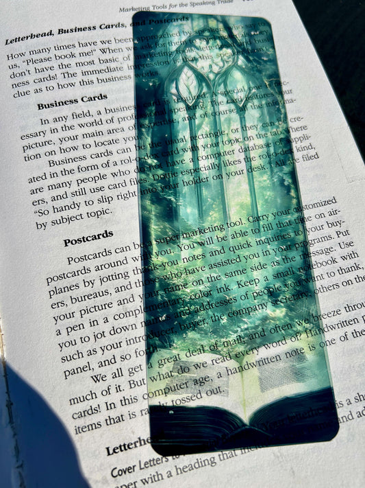 Forest Cathedral Bookmark – Gothic Arch Window Over Ancient Woods with Open Spellbook, Green Light & Dreamy Atmosphere