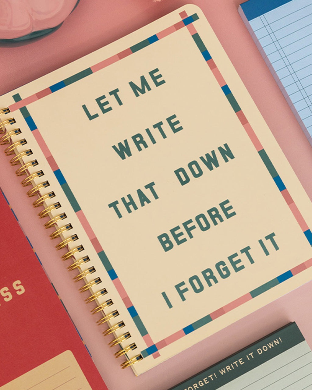 cream mini notebook with colorful striped border and teal 'let me write that down before i forget it' on a pink background