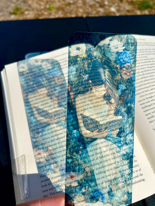 Floral fantasy bookmark with girl reading in white dress, surrounded by lush blue and white blossoms